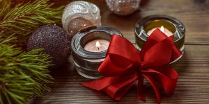 Festive Armenian Christmas scene with lit candles, red ribbon bow, ornaments, and pine branches on a wooden table