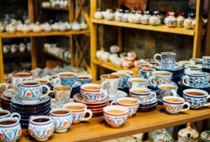 Traditional Armenian coffee cups and ceramic tea sets displayed on wooden shelves in a souvenir shop