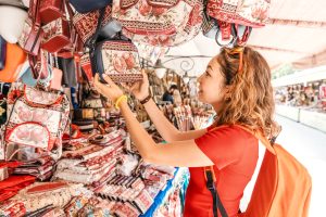 Woman choosing a handmade Armenian gift bag with pomegranate pattern at Vernissage market in Yerevan