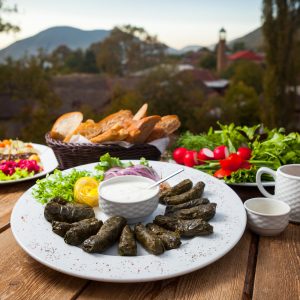 Armenian picnic table with dolma, fresh herbs, bread, and vegetables served outdoors in the mountains.