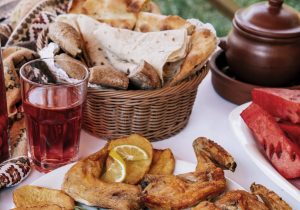 Armenian picnic with khorovats served with lemon, fresh herbs, bread, and a kompote.