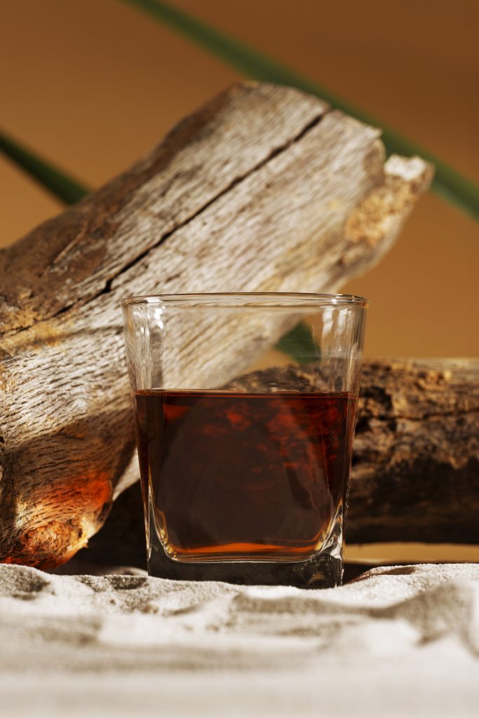 Glass of Armenian brandy beside oak wood, representing the traditional aging process