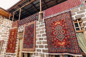 Traditional Armenian rugs hanging on a stone wall to dry, showing bold red and blue geometric patterns